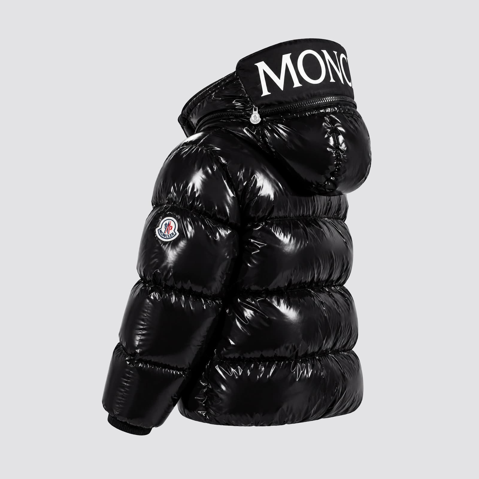 La doudoune seule, de profil : volume du matelassage, capuche zippée au lettrage blanc, écusson de manche.